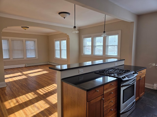 kitchen featuring decorative light fixtures, stainless steel gas range, a healthy amount of sunlight, and a kitchen island