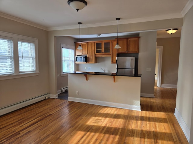 kitchen featuring appliances with stainless steel finishes, decorative light fixtures, a baseboard radiator, a kitchen breakfast bar, and dark wood-type flooring