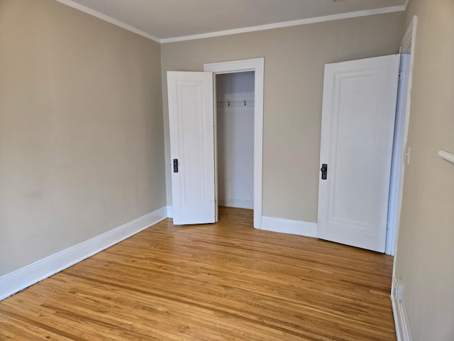 unfurnished bedroom featuring crown molding, light wood-type flooring, and a closet