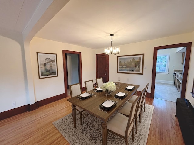 dining room with light hardwood / wood-style flooring and an inviting chandelier