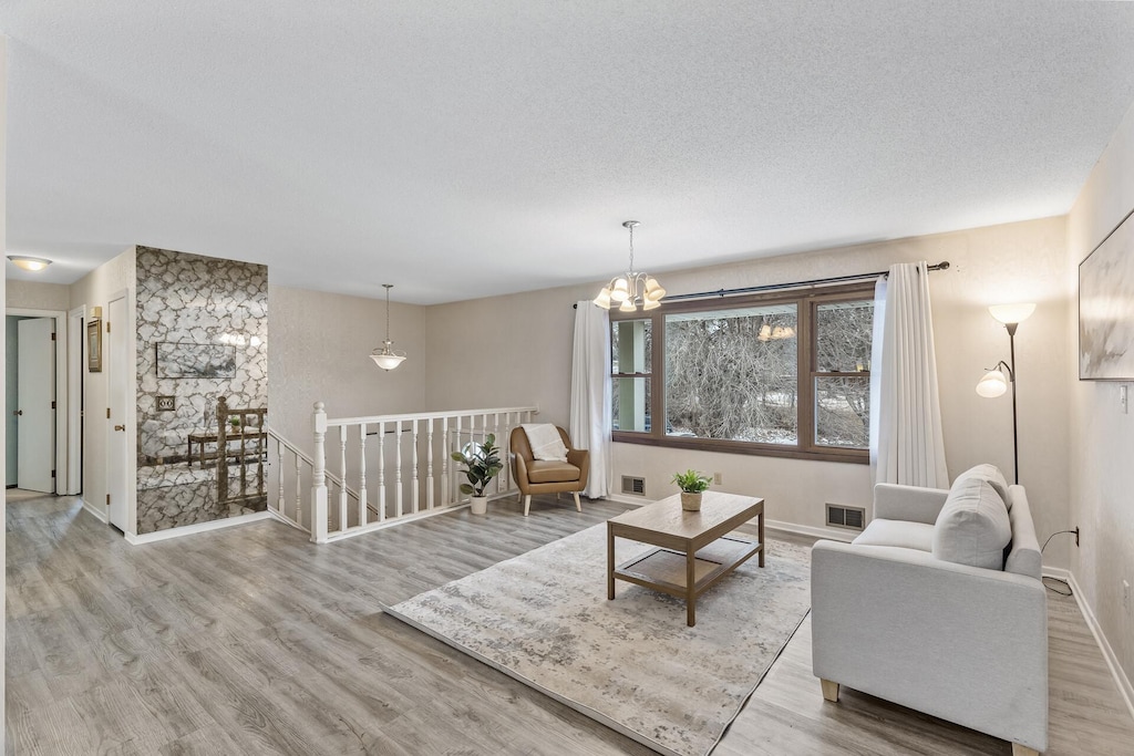 living room with a notable chandelier, light hardwood / wood-style floors, and a textured ceiling