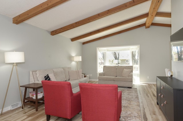 living area with vaulted ceiling with beams, a healthy amount of sunlight, and light wood-type flooring