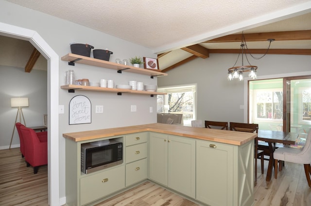 kitchen featuring green cabinetry, light wood-style floors, wooden counters, built in microwave, and a peninsula