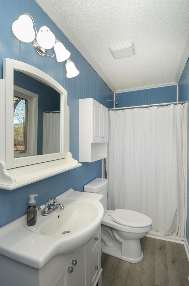 full bathroom with vanity, ornamental molding, wood finished floors, a shower with shower curtain, and a textured ceiling