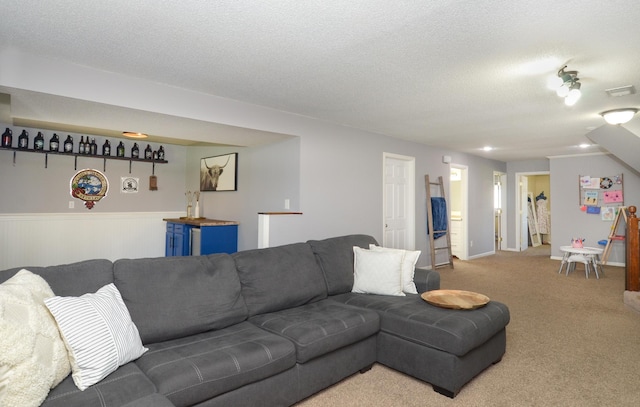 living room with visible vents, a textured ceiling, wainscoting, and light colored carpet