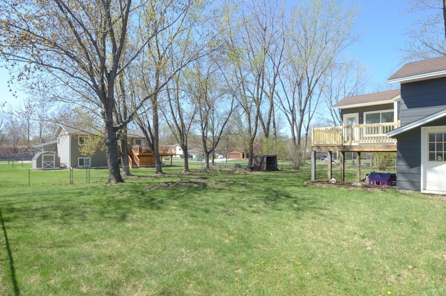 view of yard with an outdoor structure, fence, a wooden deck, and a shed