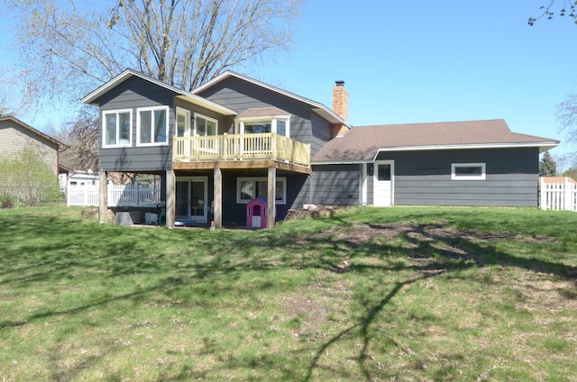 rear view of property featuring a yard, a wooden deck, and a chimney