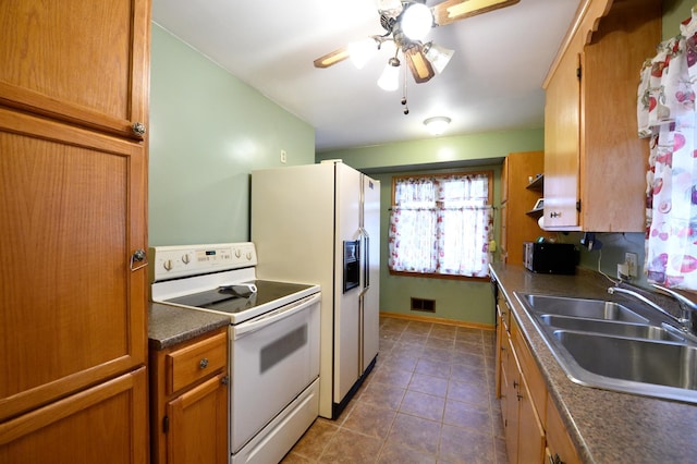 kitchen with ceiling fan, white appliances, sink, and dark tile patterned floors