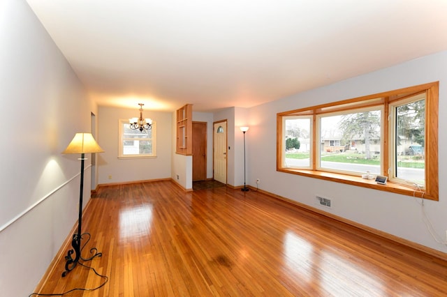 empty room with light hardwood / wood-style floors and a notable chandelier