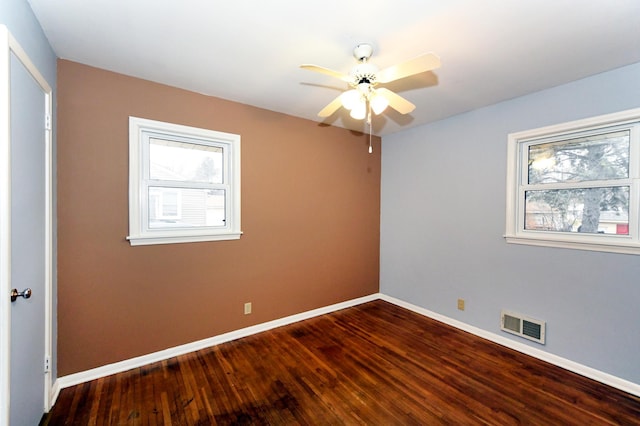 spare room with dark wood-type flooring, ceiling fan, and plenty of natural light