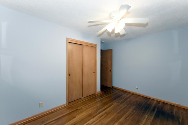 unfurnished bedroom featuring dark wood-type flooring, ceiling fan, and a closet