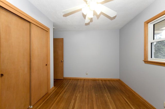 unfurnished bedroom featuring wood-type flooring, ceiling fan, a textured ceiling, and a closet