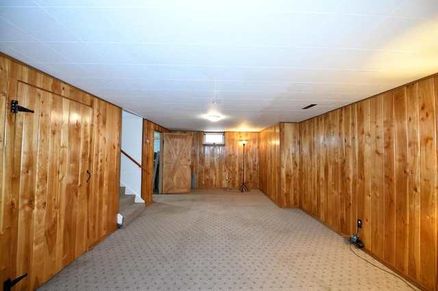 basement featuring light colored carpet and wood walls