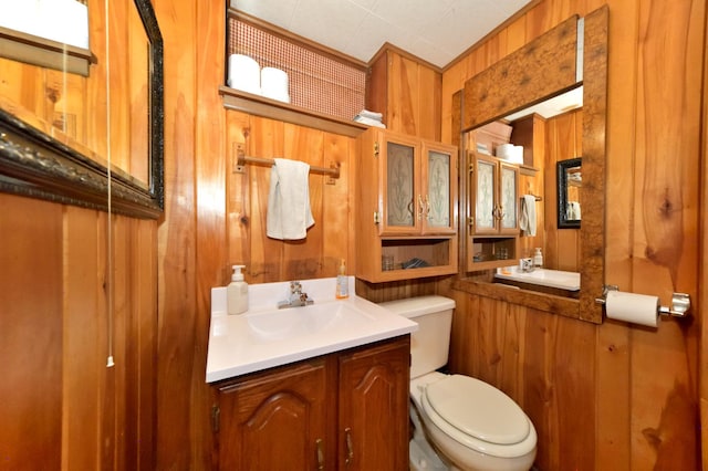 bathroom with vanity, wooden walls, and toilet