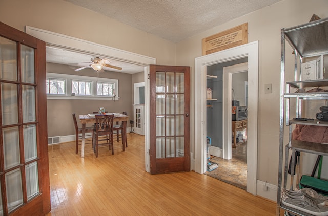 dining space featuring ceiling fan, a textured ceiling, light hardwood / wood-style floors, and french doors