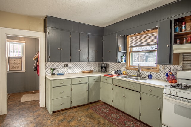 kitchen featuring plenty of natural light, sink, white gas range oven, and a textured ceiling