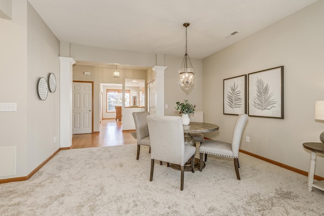 carpeted dining room with a notable chandelier and ornate columns