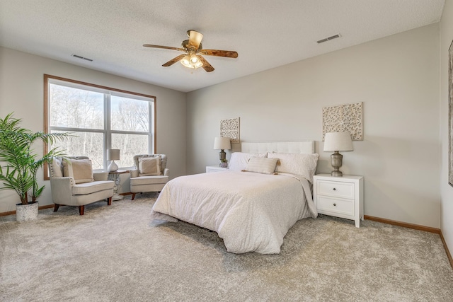 bedroom with ceiling fan, light carpet, and a textured ceiling