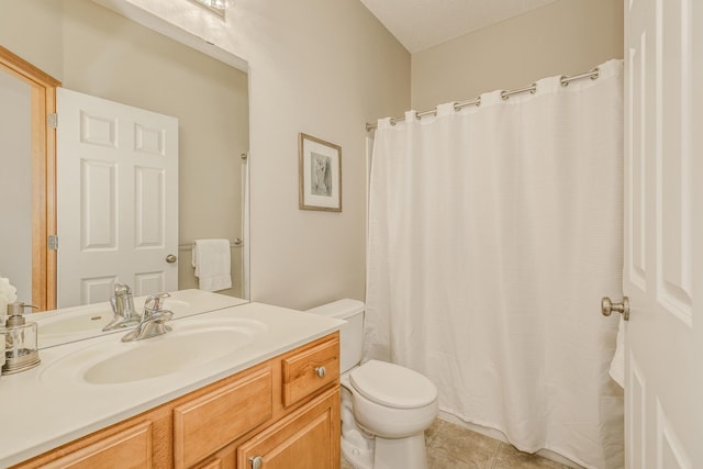 bathroom with tile patterned flooring, vanity, a textured ceiling, and toilet