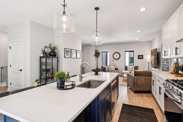 kitchen featuring gas range, sink, decorative light fixtures, and a kitchen island with sink