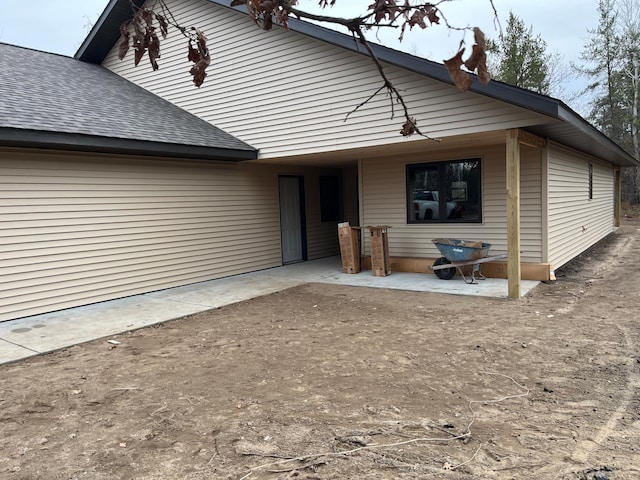 view of front of property with roof with shingles and a patio