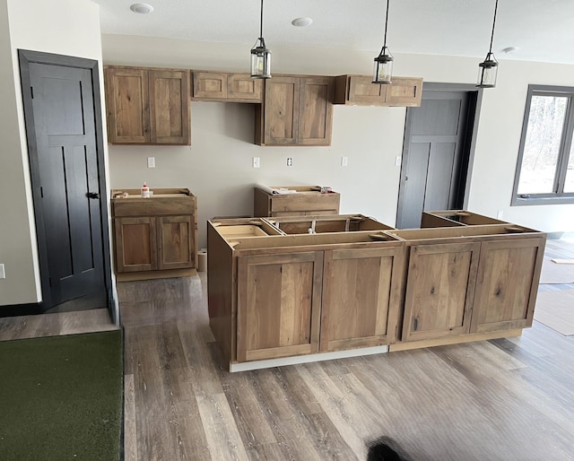 kitchen featuring decorative light fixtures, wood finished floors, and a center island
