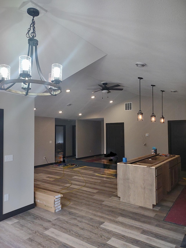 kitchen with ceiling fan, decorative light fixtures, visible vents, wood finished floors, and lofted ceiling