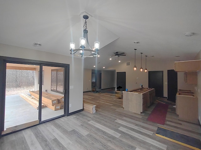 kitchen featuring a center island, ceiling fan with notable chandelier, open floor plan, light wood-style floors, and lofted ceiling