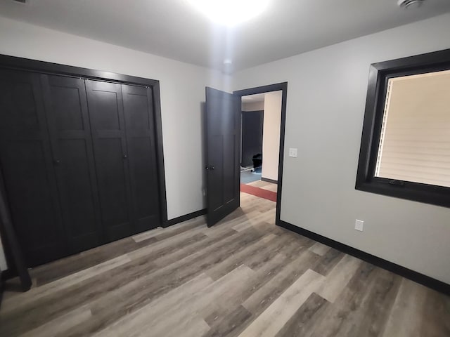 unfurnished bedroom with a closet, baseboards, and light wood-style floors