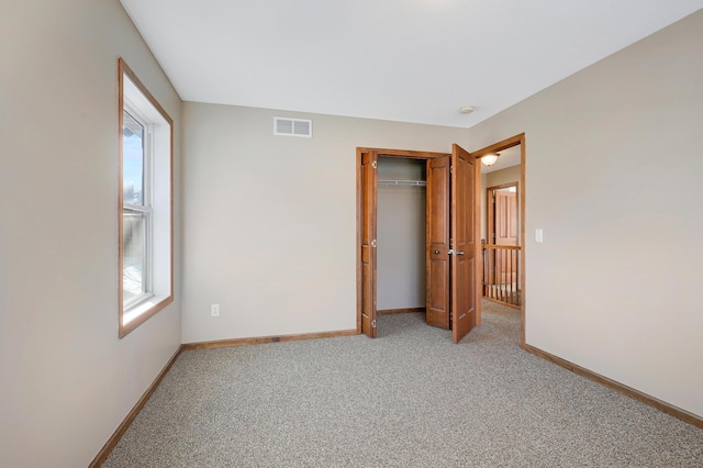 unfurnished bedroom with light colored carpet and a closet