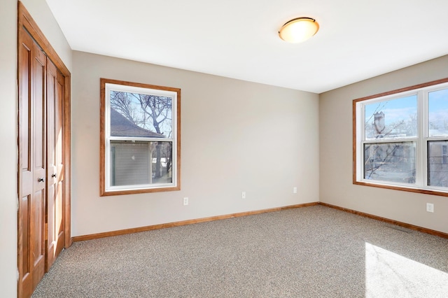 unfurnished bedroom featuring multiple windows, carpet flooring, and a closet