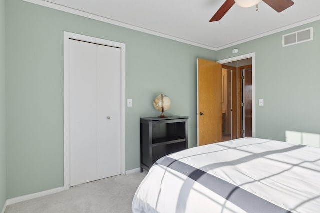 bedroom featuring ceiling fan, light colored carpet, a closet, and ornamental molding