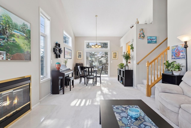 carpeted living room with a high ceiling, an inviting chandelier, and a healthy amount of sunlight