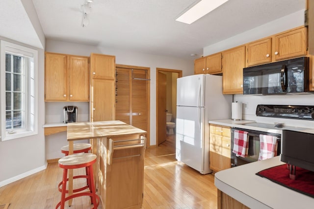 kitchen featuring electric range, white refrigerator, light hardwood / wood-style floors, and a breakfast bar