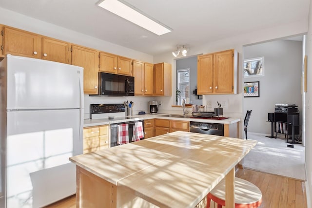 kitchen featuring sink, light brown cabinets, black appliances, and light wood-type flooring