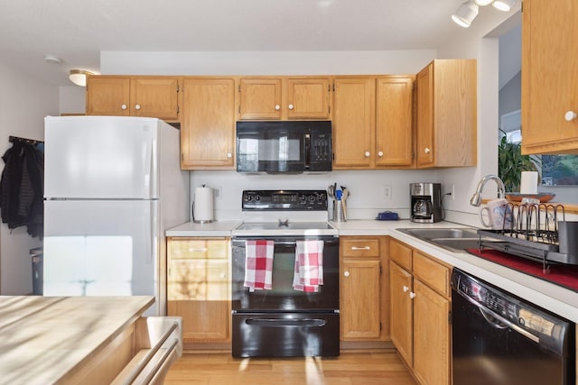 kitchen featuring black appliances, light hardwood / wood-style floors, and sink