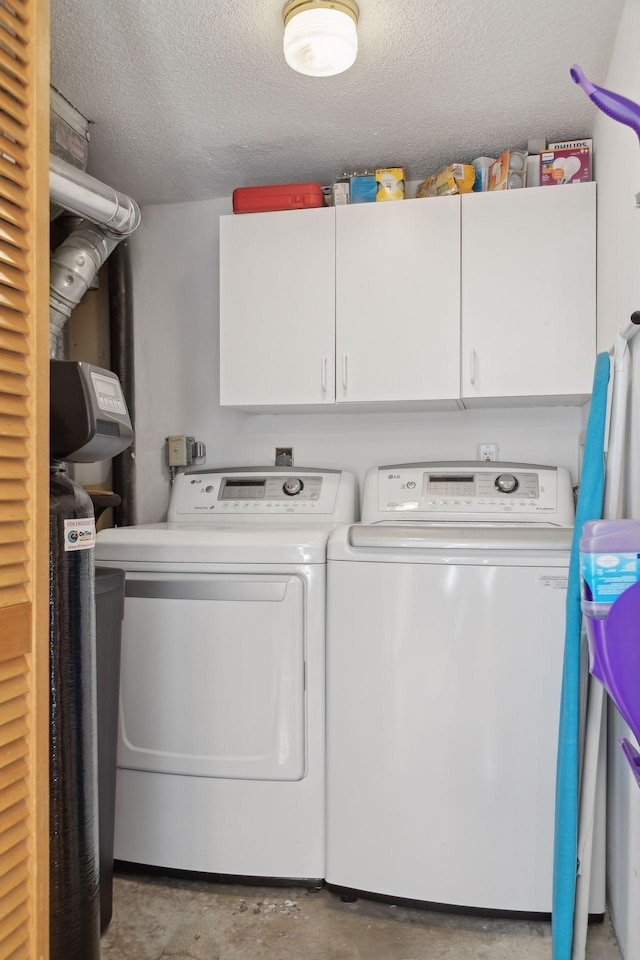 laundry area featuring cabinets, a textured ceiling, and washing machine and dryer