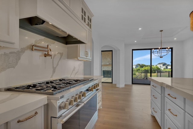 kitchen featuring white cabinetry, light stone counters, range with two ovens, and custom exhaust hood