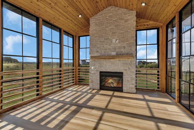 unfurnished sunroom featuring a stone fireplace, lofted ceiling, and wood ceiling