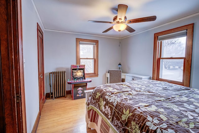 bedroom with radiator heating unit, light hardwood / wood-style floors, ceiling fan, and ornamental molding