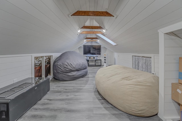 bedroom featuring vaulted ceiling with skylight, wooden ceiling, wood walls, and light wood-type flooring