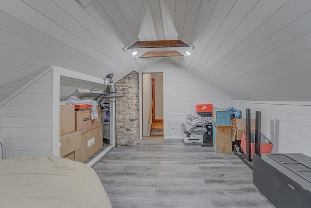 bonus room featuring wood ceiling, wood walls, vaulted ceiling with skylight, and light hardwood / wood-style flooring