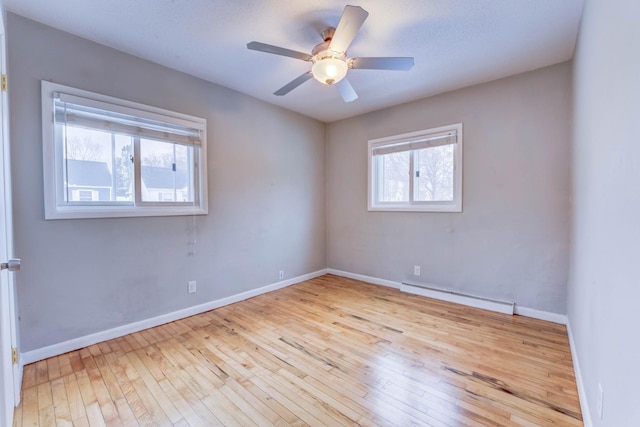 empty room featuring a baseboard radiator, ceiling fan, and light hardwood / wood-style floors