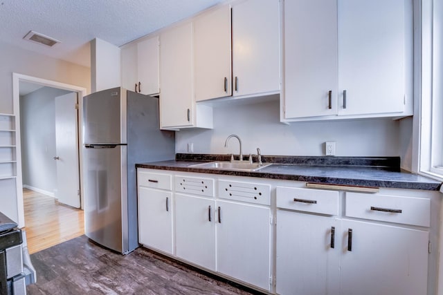 kitchen with white cabinetry, dark hardwood / wood-style flooring, stainless steel fridge, sink, and a textured ceiling