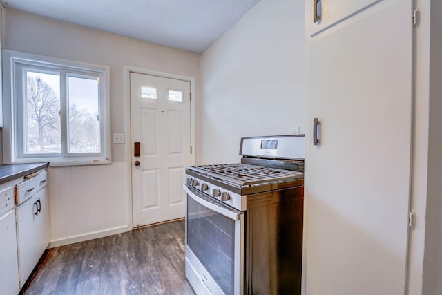 kitchen featuring dark hardwood / wood-style flooring, stainless steel gas stove, and white cabinetry