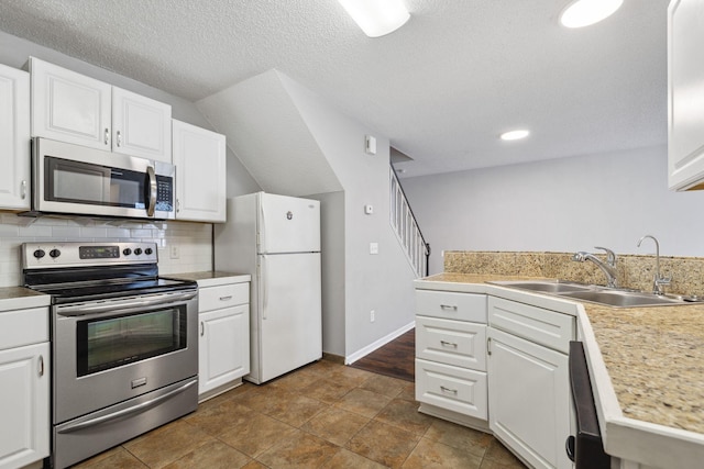 kitchen featuring stainless steel appliances, sink, white cabinets, and backsplash