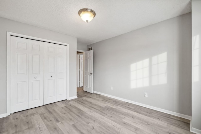 unfurnished bedroom featuring light hardwood / wood-style flooring, a closet, and a textured ceiling