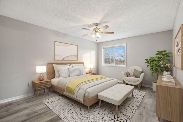 bedroom featuring ceiling fan, hardwood / wood-style floors, and a textured ceiling