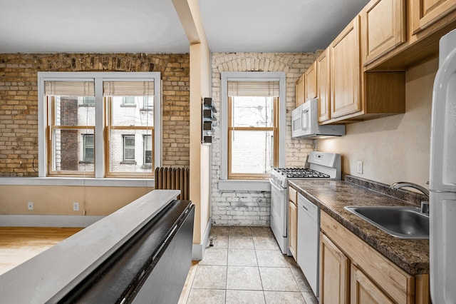 kitchen featuring light tile patterned flooring, sink, plenty of natural light, white appliances, and brick wall