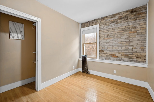 empty room featuring wood-type flooring and radiator heating unit